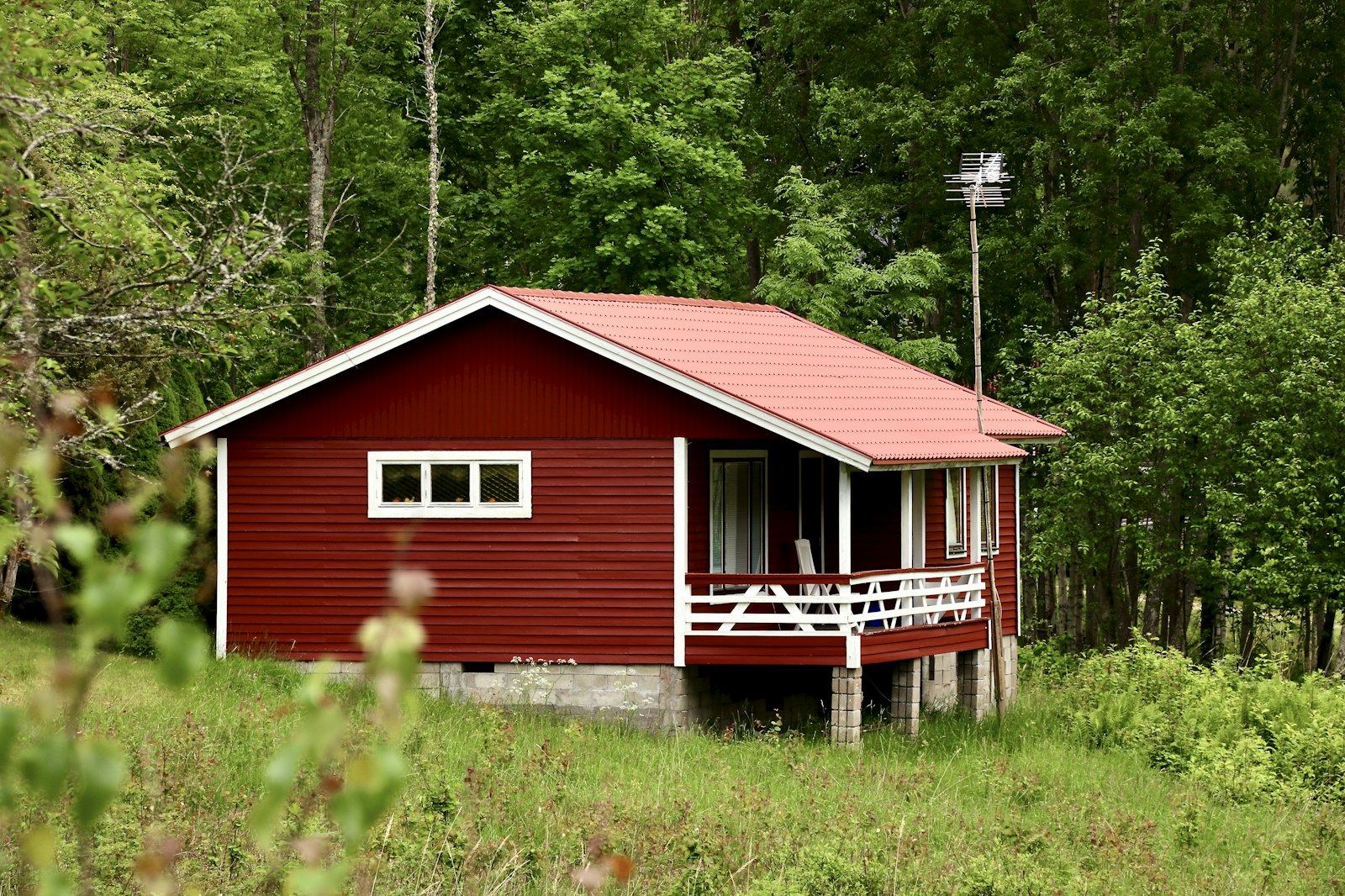 Ett bostadshus sett utifrån, med fasad, tak och tomt.
